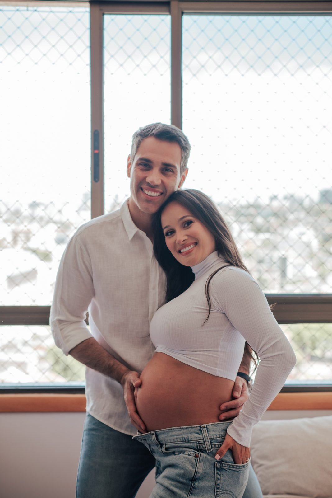 Casal grávido na sala de casa